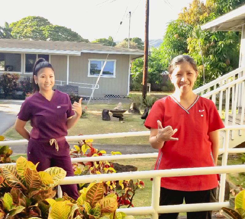Two Korean Care Home care staff giving the shaka sign outside the facility